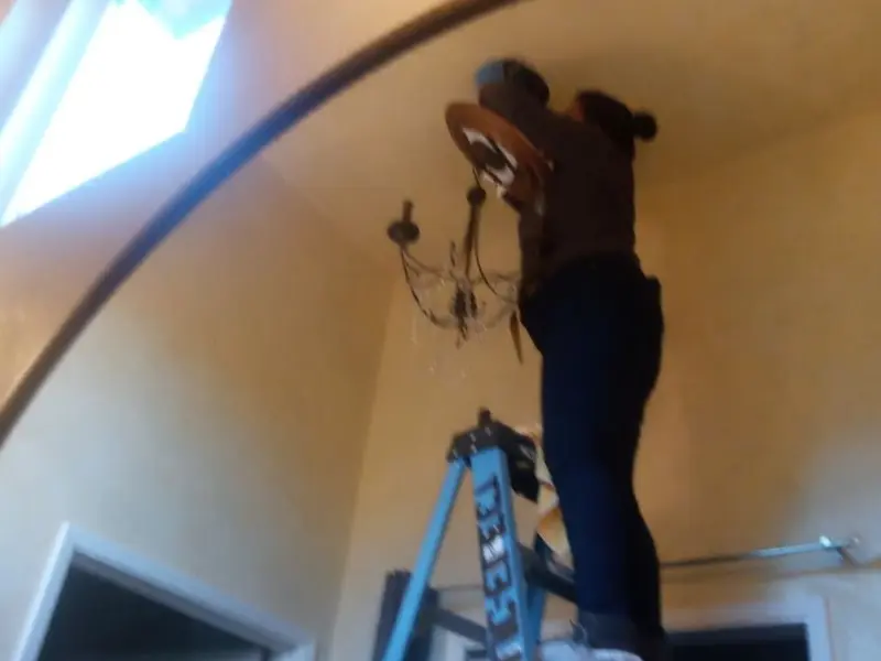 Electrician installing a chandelier in a St. Paul Park residence